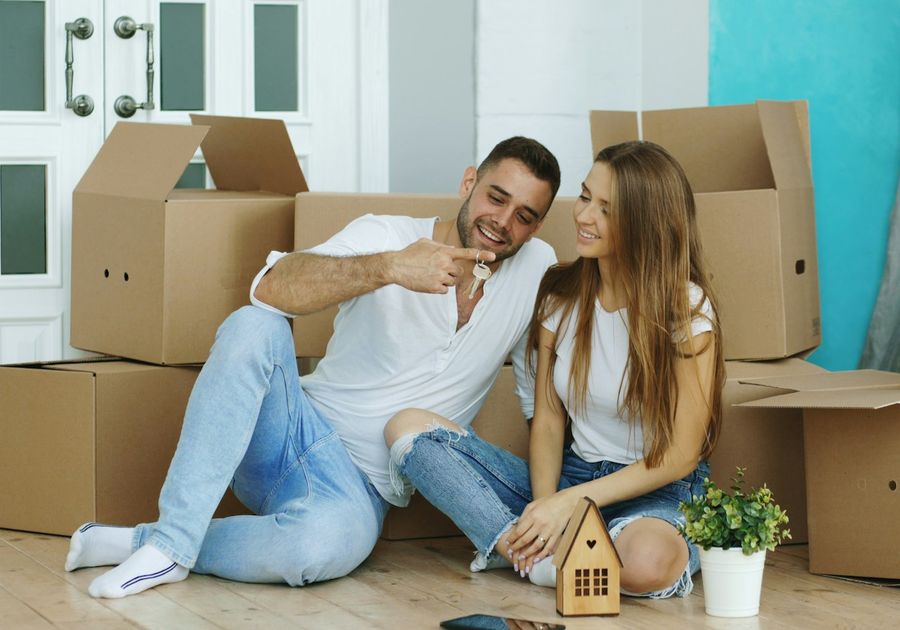 A couple sitting on the floor of their new home among moving boxes
