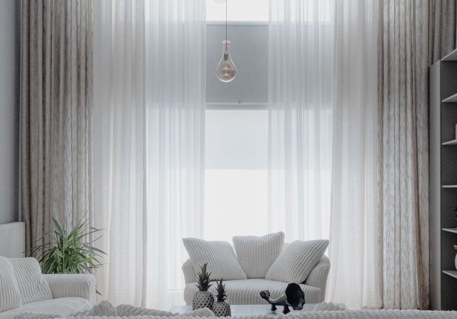A bright, freshly staged living room with white sofas and tall windows