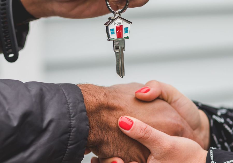 Close-up of a house key being handed from one person to another