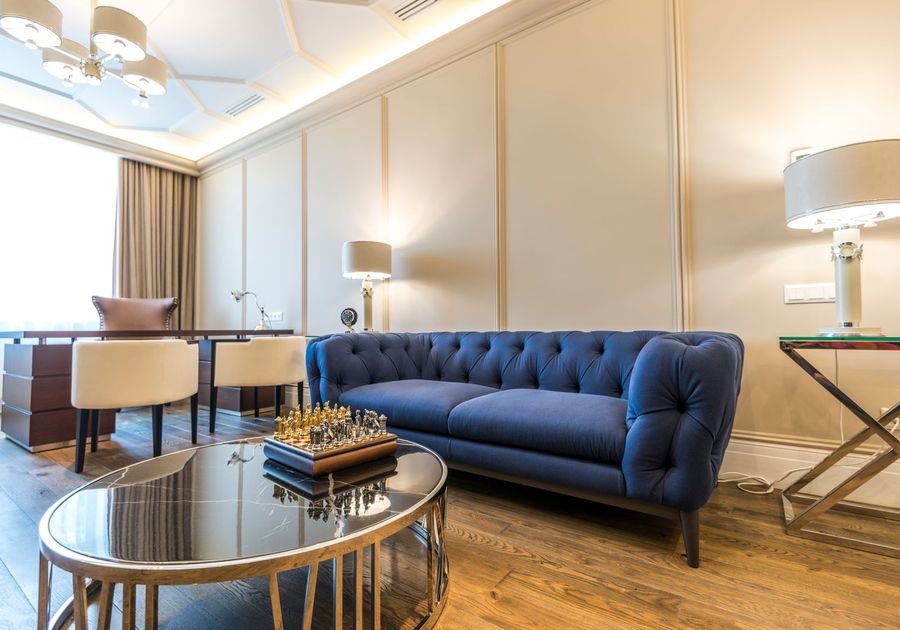 A staged living room with a blue sofa and natural light